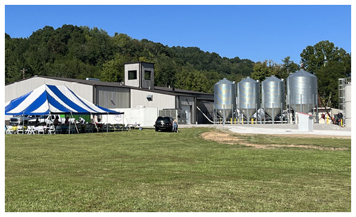 An outside view of the Southern Kentucky Distillery and outdoor equipment, as well as a blue and white striped event tent