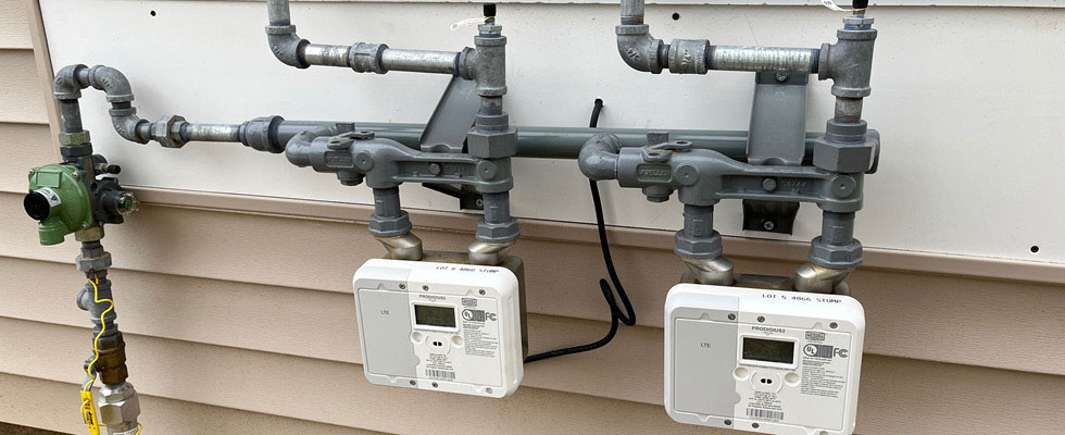 A propane meter is situated alongside the exterior of a house.
