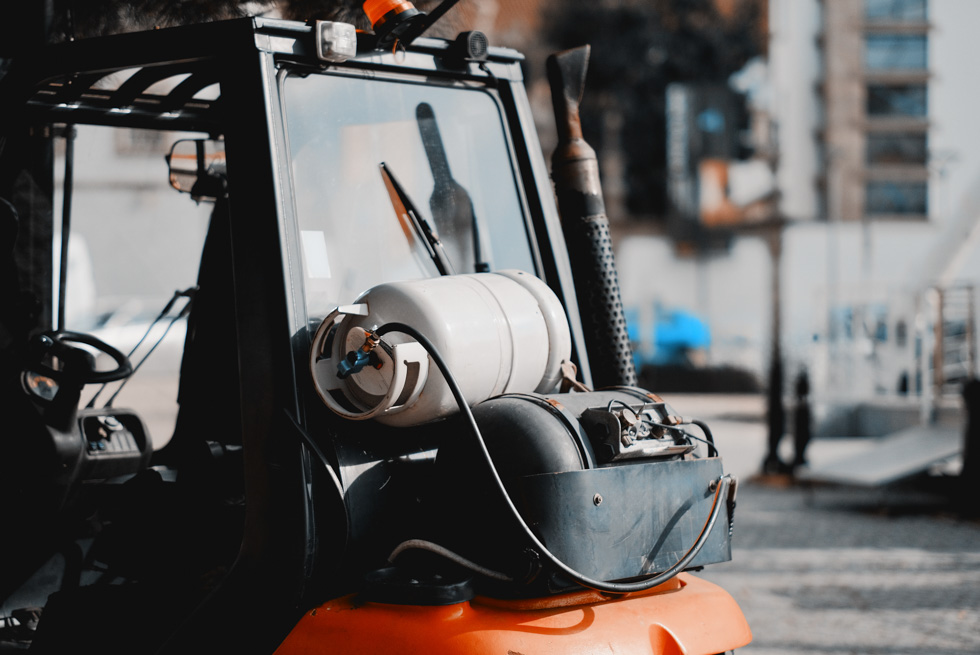 A white propane cylinder is hooked up to the back of a black and orange forklift, representing the 2026 state of the propane industry