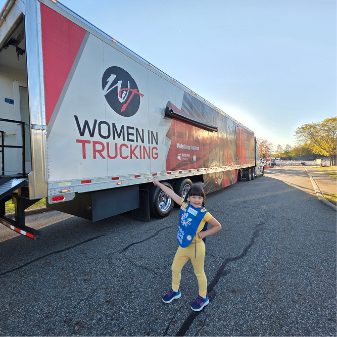 Monserrat Haney poses in front of Women in Trucking Association’s WITney trailer at the Trucks Are for Girls event