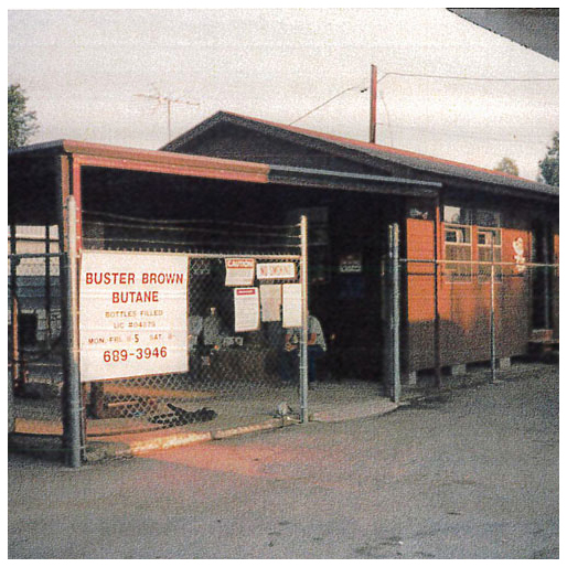 A view of the Buster Brown building with a sign that reads "Buster Brown Butane" hanging on a fence
