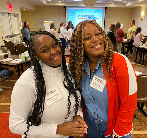 Two participants in a workplace training session stand together and smile. Photo provided by ThompsonGas.