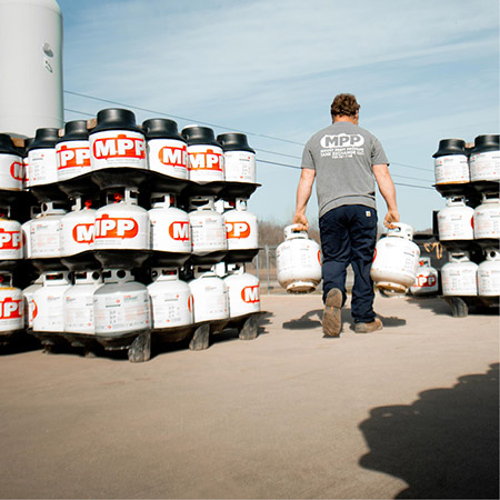 An MPP worker carries a propane cylinder tank into storage.