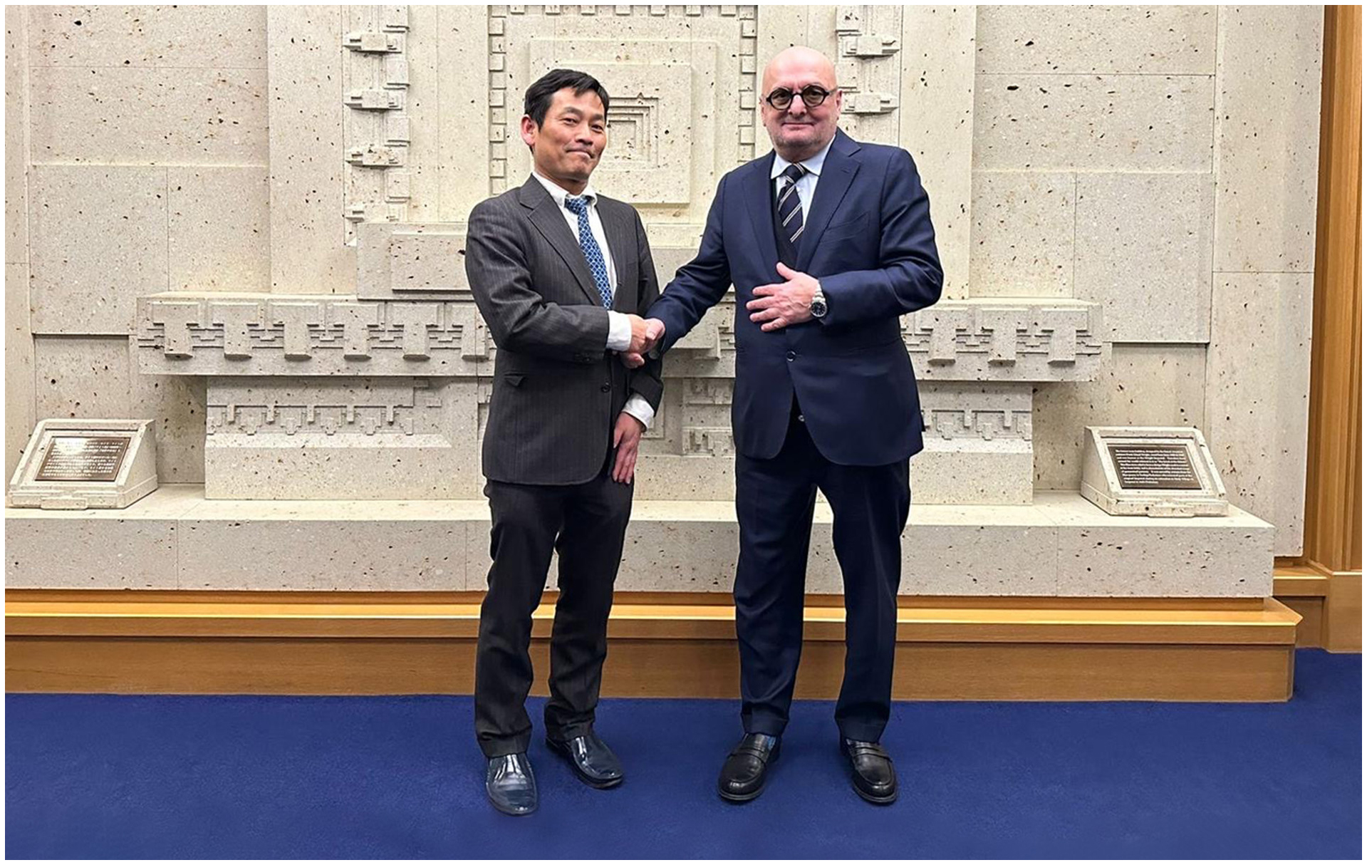 Makoto Kohda and Ezio Cavagna shaking hands, celebrating their business deal.