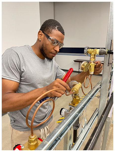 A man in safety glasses practices working on a propane piping system