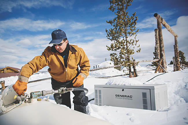 A man bends down in the snow, preparing an indiscriminate piece of equipment.