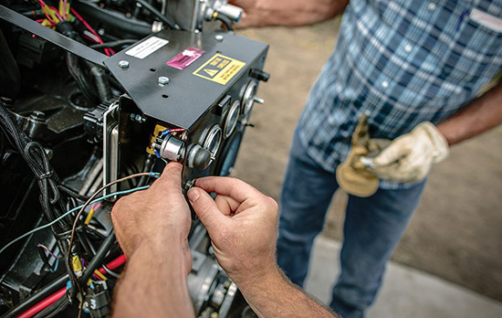 A propane-powered engine is being prepared by several workers for agricultural use.