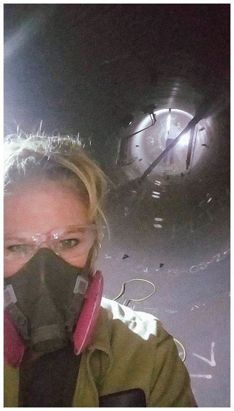 Cathy Maloy takes a selfie in front of equipment while wearing a heavy-duty protective face mask and safety glasses