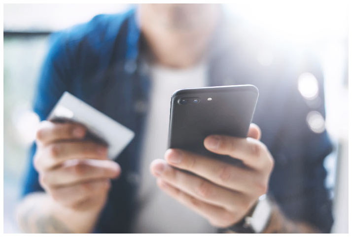 A person holding a credit card in one hand and a mobile phone in the other