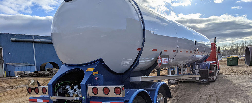 A view from the back of a white tank transport on a blue transport trailer.