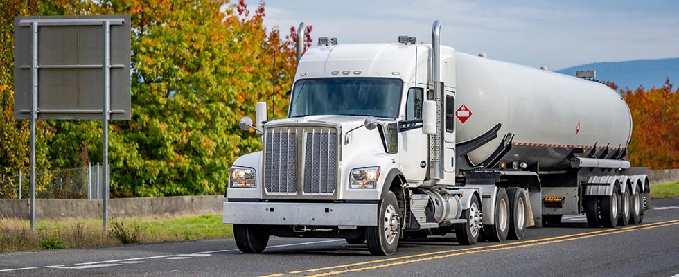 A white propane hauler is depicted driving down the road.