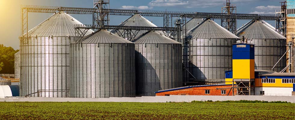 Eight grain silos on a farm standing next to a propane-powered irrigation system