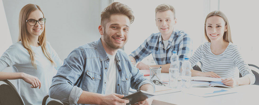 Four young professionals gather around a table in an office setting