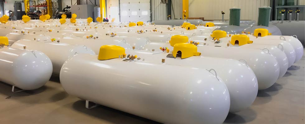 Pristine, shining refurbished propane tanks are on display as they sit next to each in a warehouse.