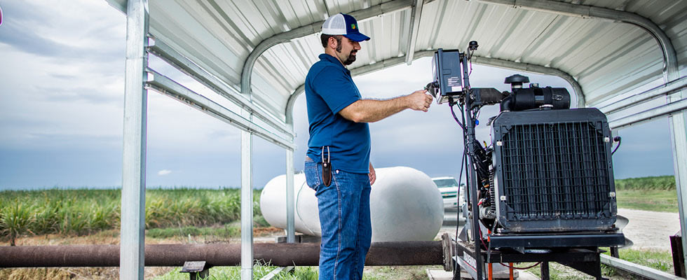 A man checks a propane device on a farm.