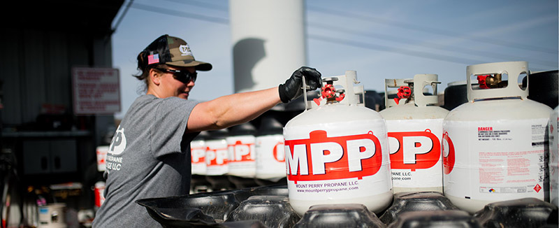 An MPP worker loads a cylinder tank onto a rack.