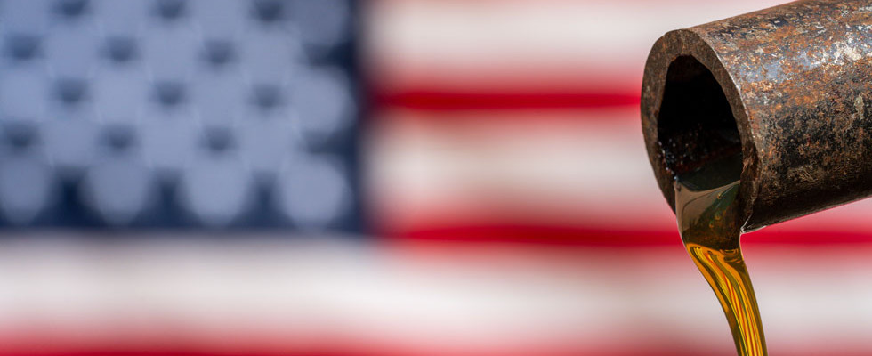 A pipeline drips propane supply oil against the backdrop of an American flag.