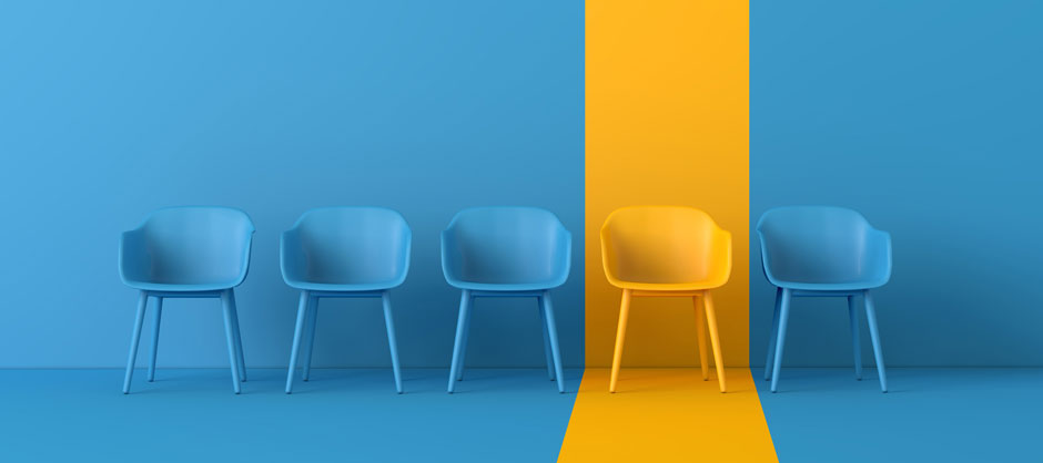 Five chairs in a row (three blue, one yellow, then one blue) on a blue background with a yellow spotlight on the yellow chair