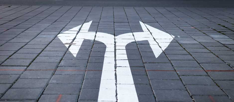 An arrow that splits into two and points left to right painted on a street pathway