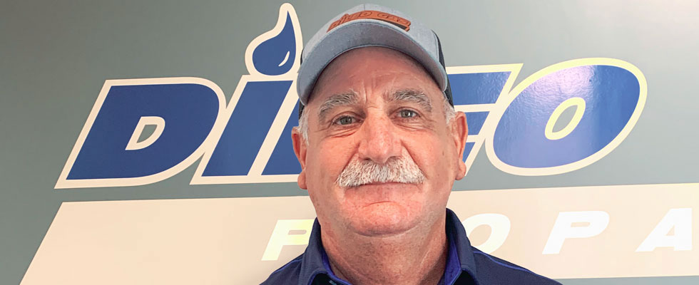 Paul DiLeo Sr. smiles in front of DiLeo Gas Inc. logo