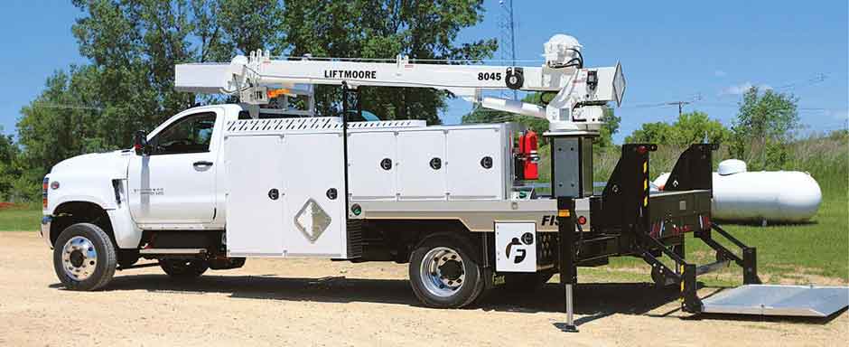 A white propane service truck from Fisk Tank Carrier with an aboveground propane tank in the background