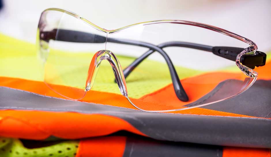 PPE glasses sitting on top of an orange, yellow and gray PPE vest