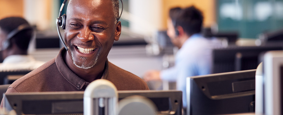 A customer service representative smiles while using a headset.