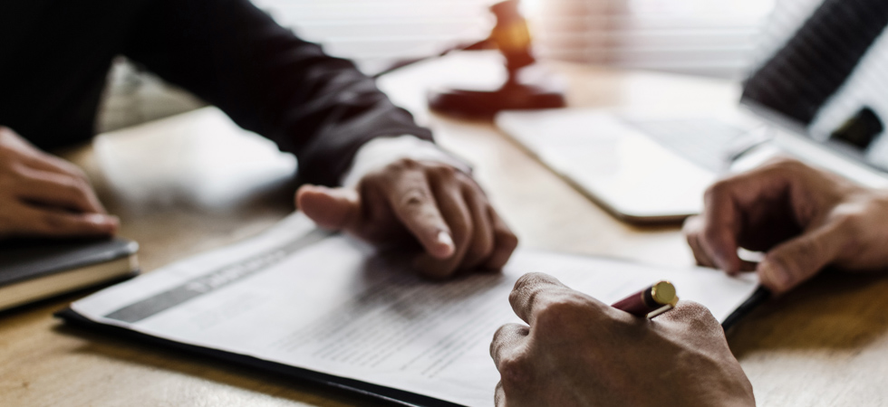 Hands mull over a legal document, showcasing the importance of indemnification clauses