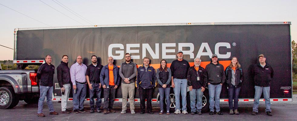 The Generac team stands in front of a trailer with the Generac logo