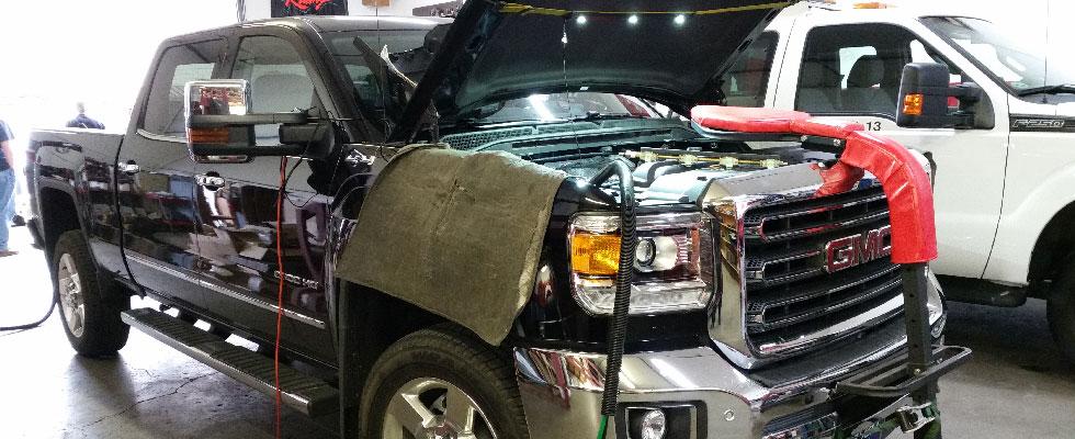 A truck in a repair shop with the hood open, undergoing an autogas conversion.