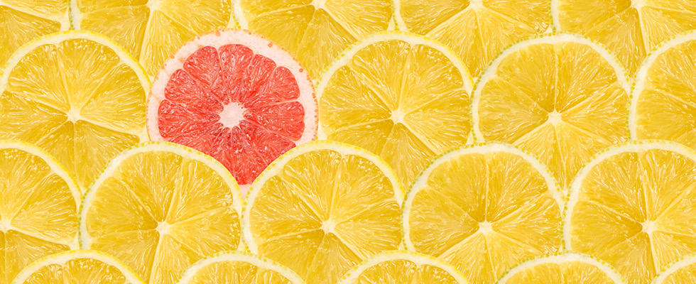 A single red grapefruit slice standing out among a crowd of yellow lemon slices