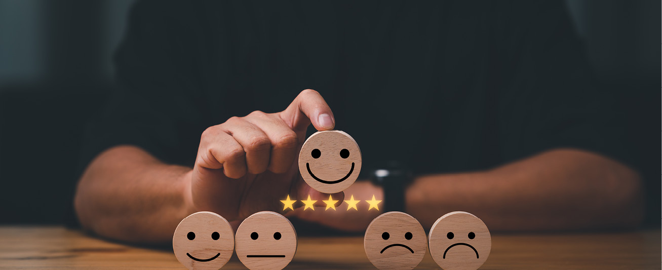 An image depciting a hand holding a smiling face with five stars underneath it represents delivering excellent customer service.
