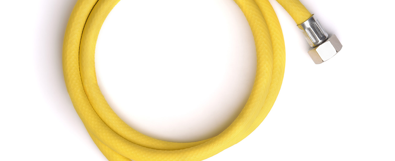 A yellow, flexible corrugated stainless-steel tube is pictured against a white backdrop.