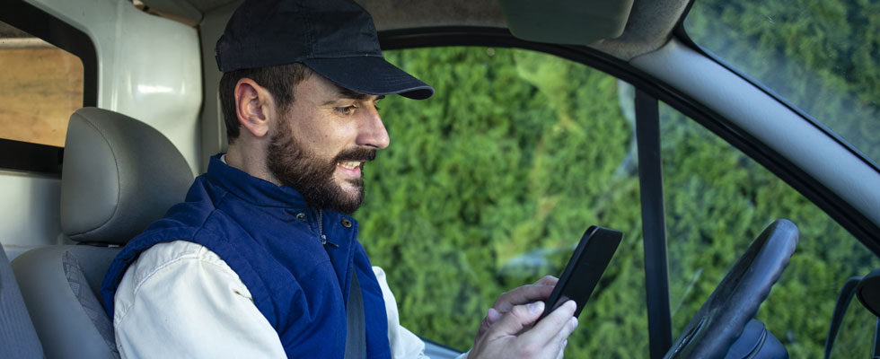 A delivery driver uses a mobile device in the cab of his truck to complete mobile driver documentation
