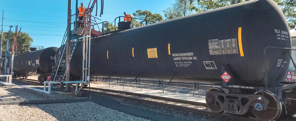 Rail workers in PPE work on a propane transport rail car tank