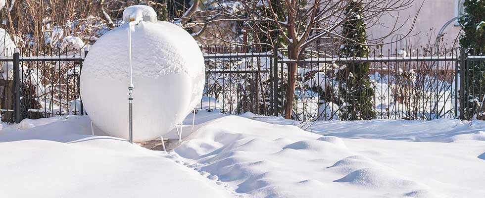 A propane tank is pictured outside on the snow-covered ground.