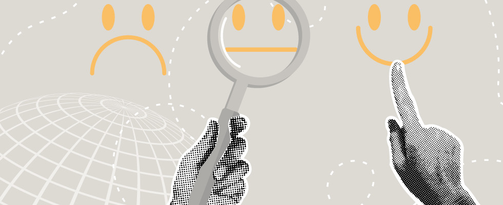 Two hands point and hold up a magnifying glass on a frowny face, a neutral face and a smiling face.