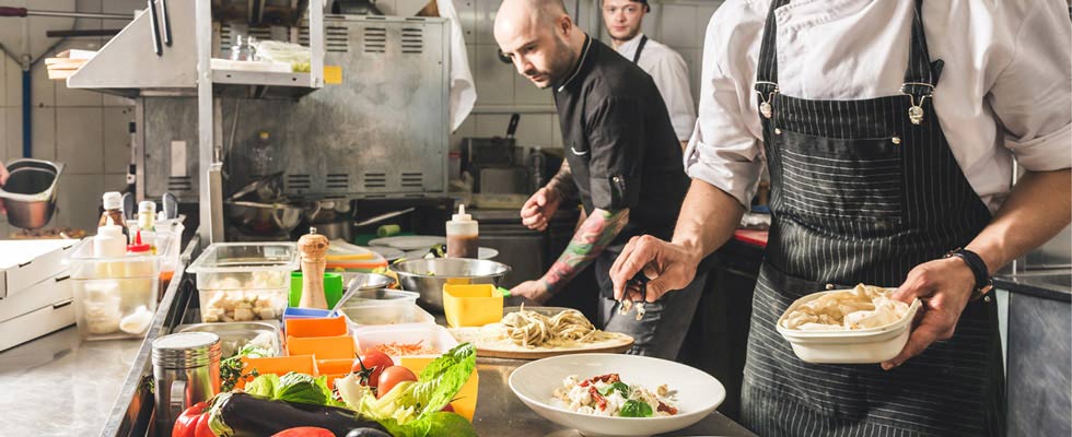 Chefs prepare a colorful dish in a restaurant, excercising the same care needed for succession planning