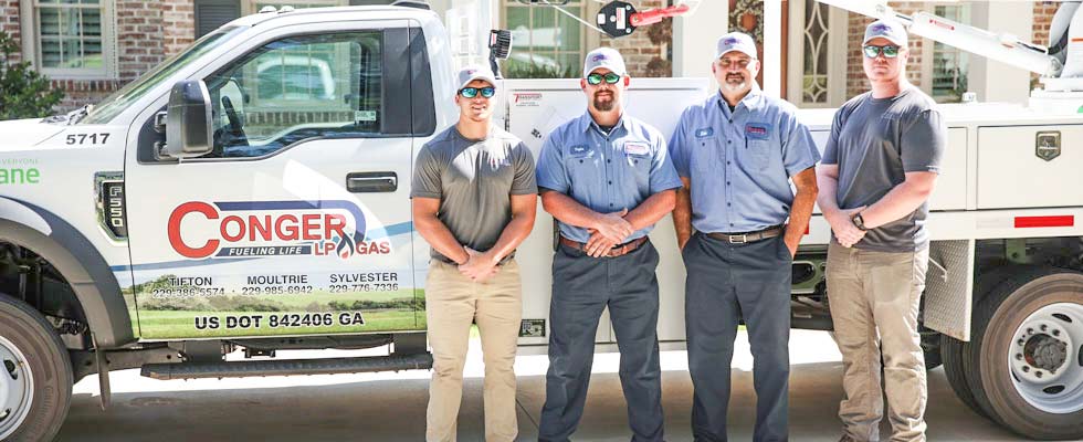 Four Conger LP Gas team members stand in front of a Conger truck for a photo
