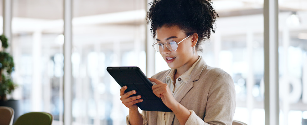 A woman looks at a tablet in an office setting.