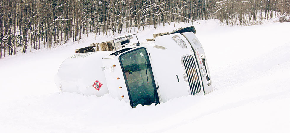 A white bobtail truck turned over on its side in the snow due to shifting center of gravity