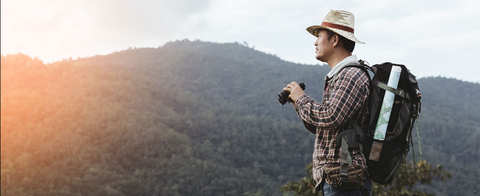 A man with binoculars looks to the distant mountains.