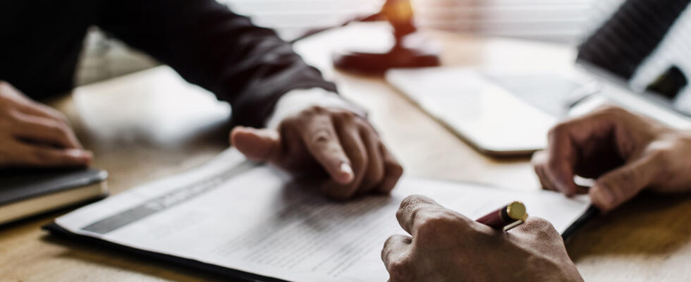 Hands mull over a legal document, showcasing the importance of indemnification clauses