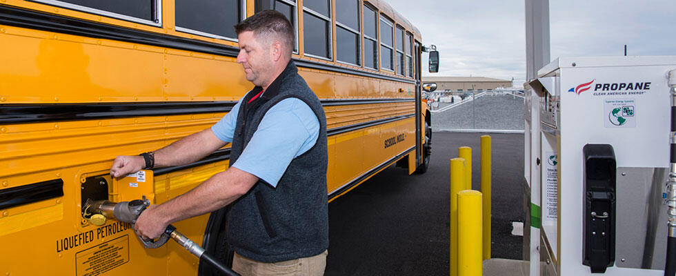 A man fills a school bus at with an autogas fueling dispenser.