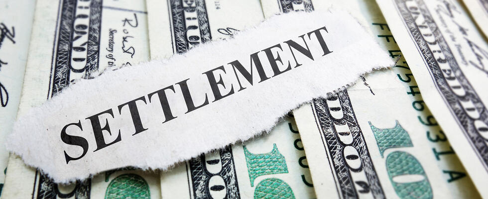The word "settlement" is pictured against a stack of money.