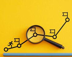 A stick figure runs up a line graph with flags marking different goals met