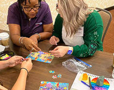 Participants in a workplace training session work together at a table to complete a multi-colored puzzle. Photo provided by ThompsonGas.