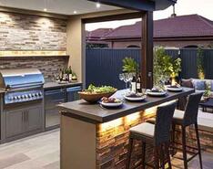 An outdoor propane-powered kitchen with a bar seating area on an outdoor patio