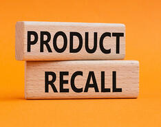 Two stacked wooden blocks with the words "product recall" on an orange background
