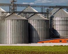 Eight grain silos on a farm standing next to a propane-powered irrigation system